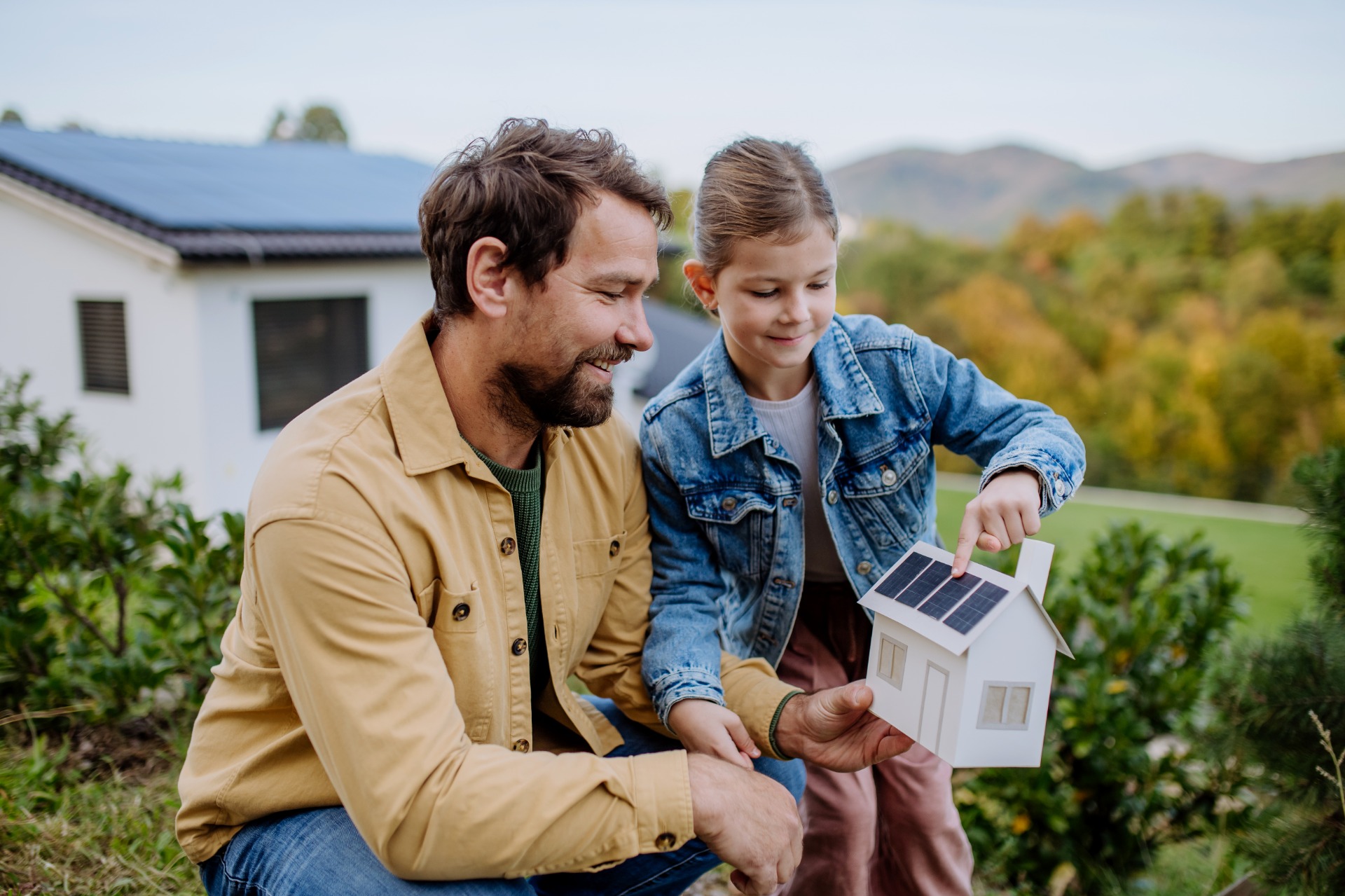 Photo d'un père avec sa fille en train de regarder une maquette de projet de rénovation énergétique